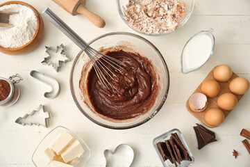 Bowl with fresh chocolate dough and ingredients on white wooden background