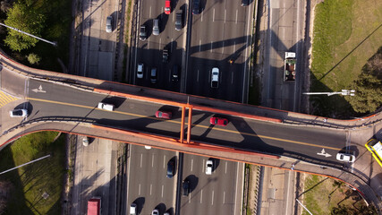 Aerial top down view of Bridge over Panamerican Highway in Buenos Aires, Argentina. Busy traffic on the road of Buenos Aires under red bridge.