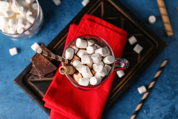 Glass cup of tasty hot chocolate with marshmallows on blue background