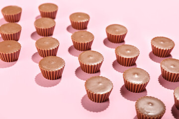 Tasty peanut butter cups on color background