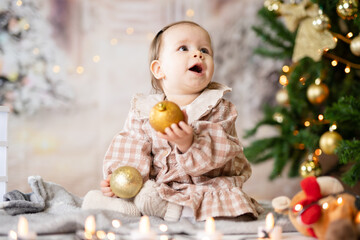 One small caucasian baby girl sitting playing with Christmas decoration