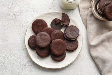 Plate with tasty chocolate cookies and mason jar of milk on light background