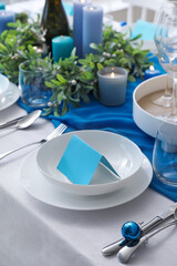Dining table with setting for Christmas celebration and blank card indoors