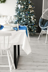 Dining table with setting for Christmas celebration in festive room