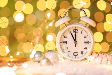 Stylish New Year clock, Christmas decor and snow on table against blurred background