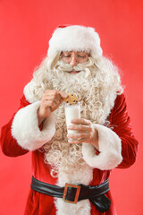 Santa Claus with tasty cookie and glass of milk on color background