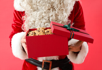 Santa Claus with tasty cookies in gift box on color background