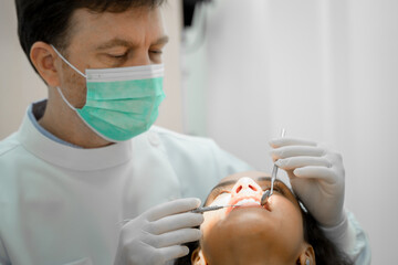 Fototapeta na wymiar Dentist holding a tooth mirror and dental pick are performing dental exam on a patient in dental clinic