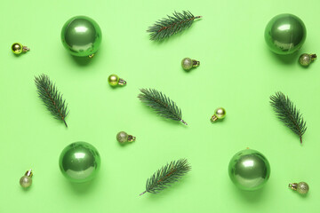 Beautiful Christmas balls and fir branches on green background