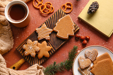 Wooden board with sweet Christmas gingerbread cookies and cup of coffee on red background
