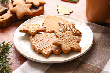 Plate with sweet Christmas gingerbread cookies on red background