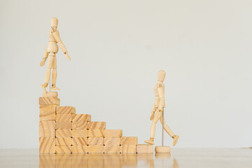 2 wooden puppets walk up the wooden steps blocks to create a business growth idea.