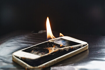 burning broken smartphone on a black background. 