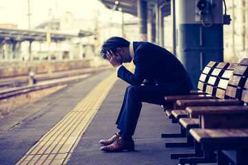 駅のホームで落ち込む男性　train