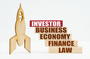 On the white surface there is a wooden rocket and planks, on the red plaque the inscription - INVESTOR