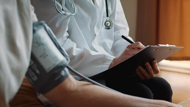 Unrecognizable Doctor Measuring Arterial Blood Pressure For Senior Patient Indoor