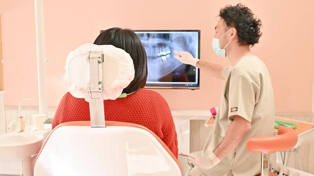 歯科医院で患者さんに説明するドクターの様子	
