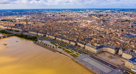 Aerial view of Bordeaux cityscape on banks of Garonne river overlooking Gothic spire of Basilica of St. Michael, France..