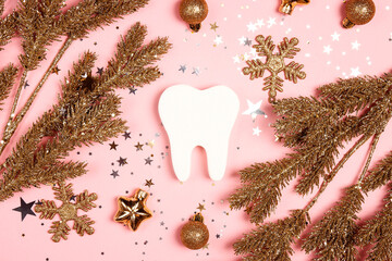 White tooth with gold decorations and fir branches on pink background. Dentist Merry Christmas and...