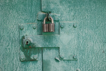 Padlock on rusty metal door . Close up view