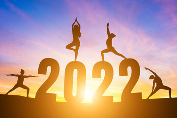 Happy New Year Numbers 2022, Silhouette woman practicing yoga early morning sunrise over the horizon background, Health and Happy new year concept.