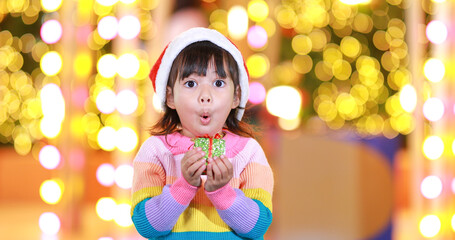 Fototapeta na wymiar New year anticipation.The cute little girl Wearing a red Christmas hat and beautiful color shirt on a christmas background with bokeh lights .Have fun and have fun during this important season.