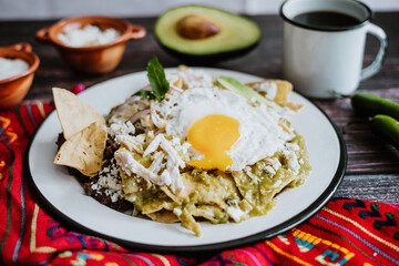 Mexican green chilaquiles with fried egg, chicken and spicy green sauce traditional breakfast in...