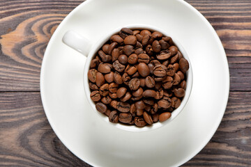 A white coffee mug filled with fragrant coffee beans stands on an old tree
