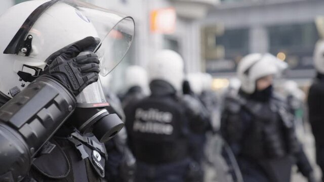 Armed police officer with gas mask to protect from tear gas. Outfit and helmet to execute law enforcement against rioting crowd of people.