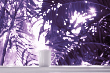 Palm tree leaves and cup of tea violet color toning, color of the year Very Peri
