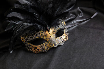 Carnival Venetian golden mask with feathers on black color background, female disguise, masquerade