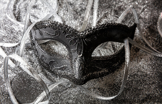 Carnival Venetian black mask on shiny grey color background, female disguise, masquerade