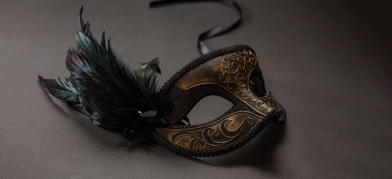 Carnival party. Venetian female mask with feathers on black color background, masquerade, copy space