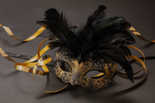 Carnival Venetian golden mask with feathers on black color background, female disguise, masquerade