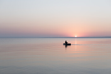 Sea at dawn with fishing rubber boat, calm, Sea of Azov, Russia.