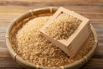 Brown rice in a wooden box set against a wooden background.