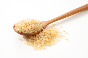 Brown rice in a wooden spoon placed on a white background.