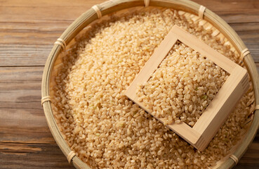 Brown rice in a wooden box set against a wooden background.