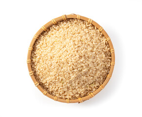 Brown rice in a bamboo colander set against a white background.