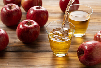 Apple juice in a glass cup against a wooden background.