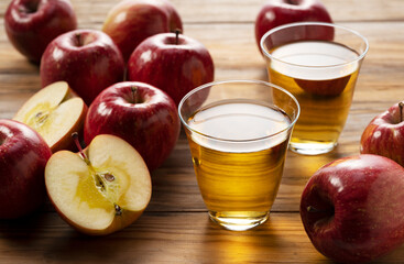 Apple juice in a glass cup against a wooden background.