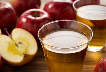 Apple juice in a glass cup against a wooden background.