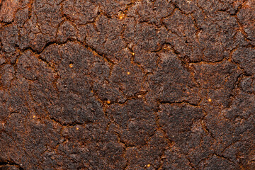 Cracked surface of freshly baked brown rye bread in close-up