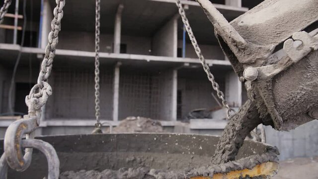 concrete pours from a concrete mixer at a construction site