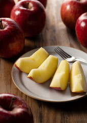 Naklejka na ściany i meble Cut apples on a plate against a wooden background.