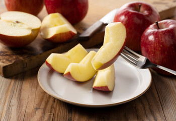 Fototapeta na wymiar Cut apples on a plate against a wooden background.
