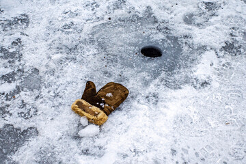 The fur glove lies on the ice of the river near the fishing hole