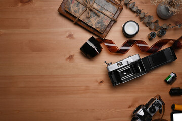 Top view film rolls, retro camera and book on wooden table.