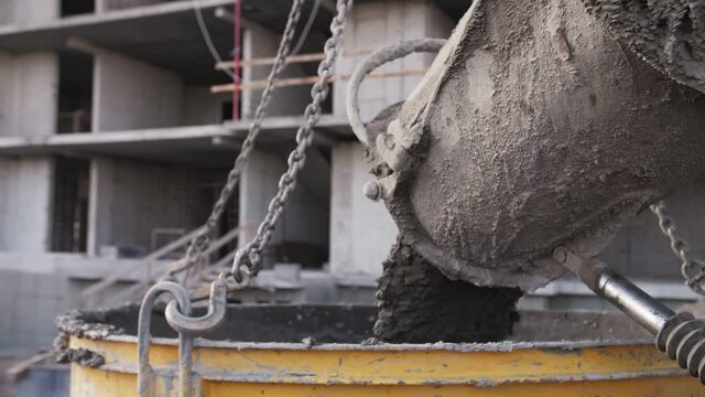 concrete pours from a concrete mixer at a construction site