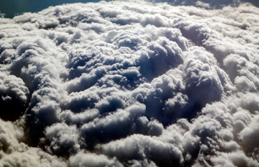 Aerial view from airplane window at high altitude of dense puffy cumulus clouds forming before...